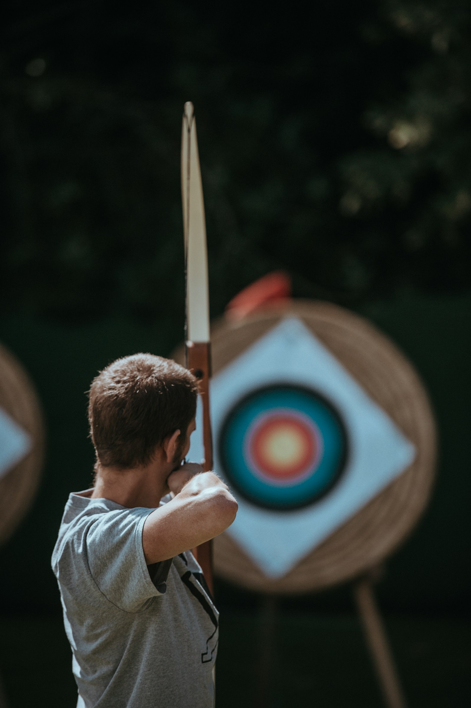 An archer drawing a recurve bow toward a target