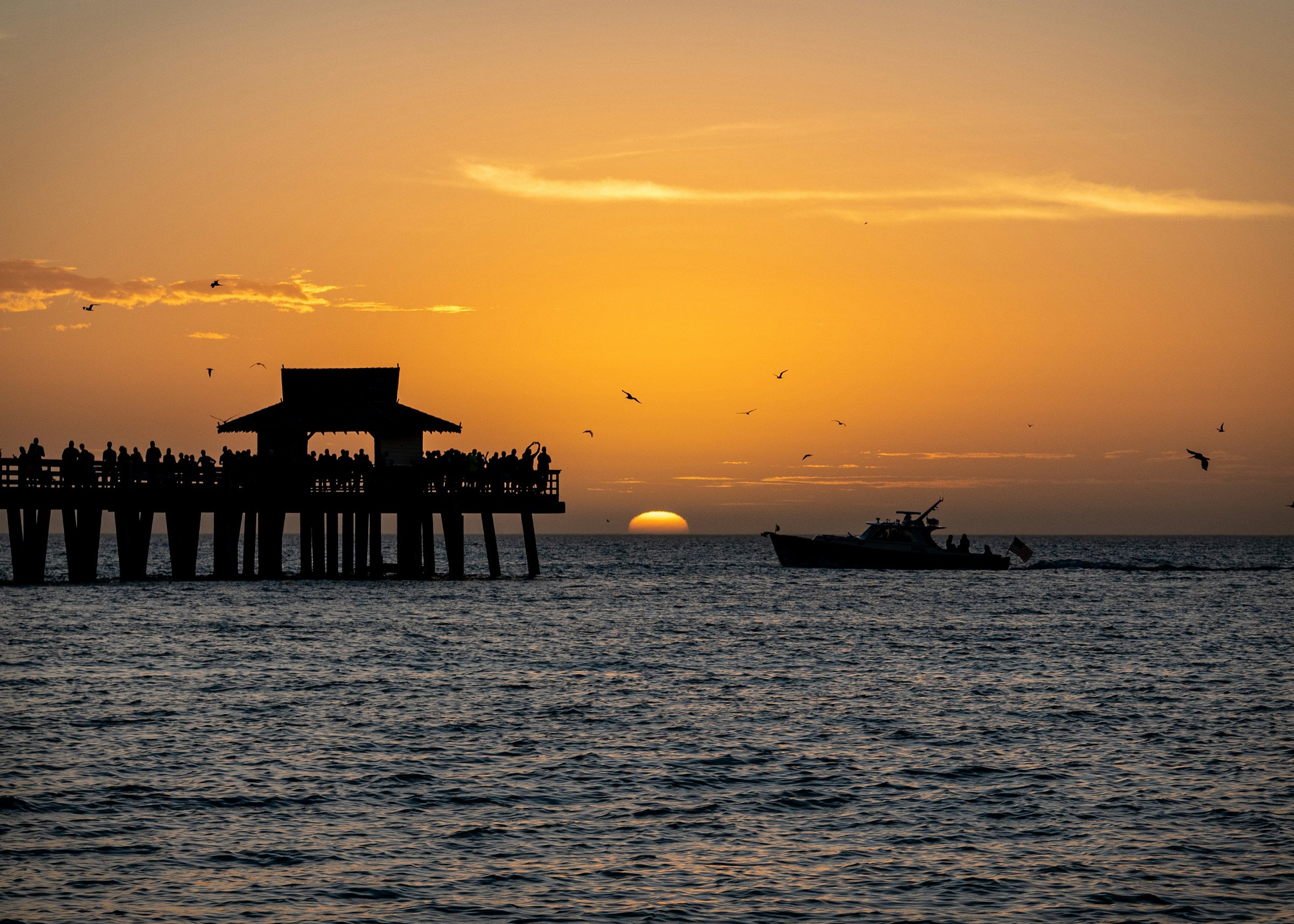 A pier and a fishing boat silhouetted against a Gulf Coast sunset