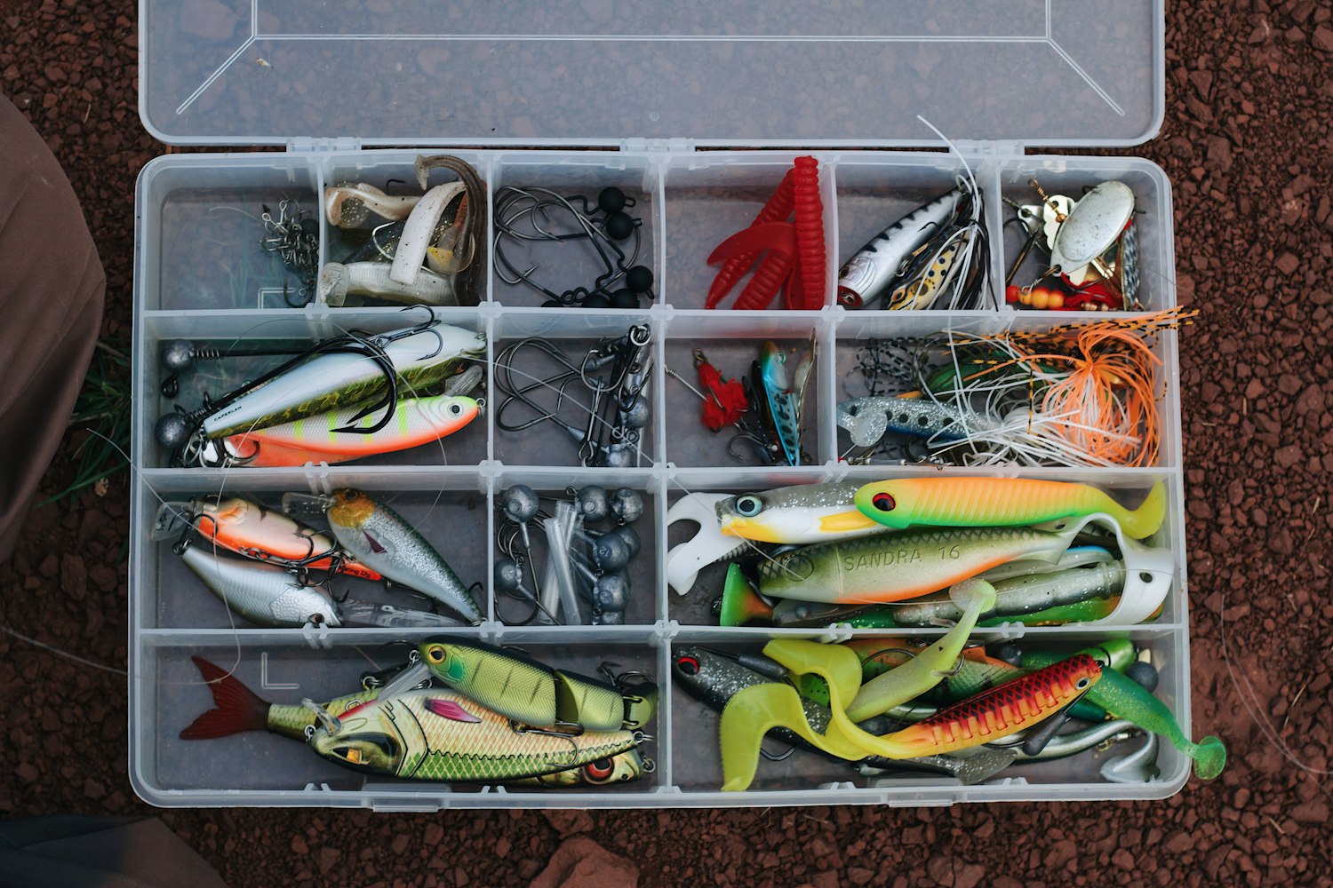 An open tackle box full of soft plastics and lures